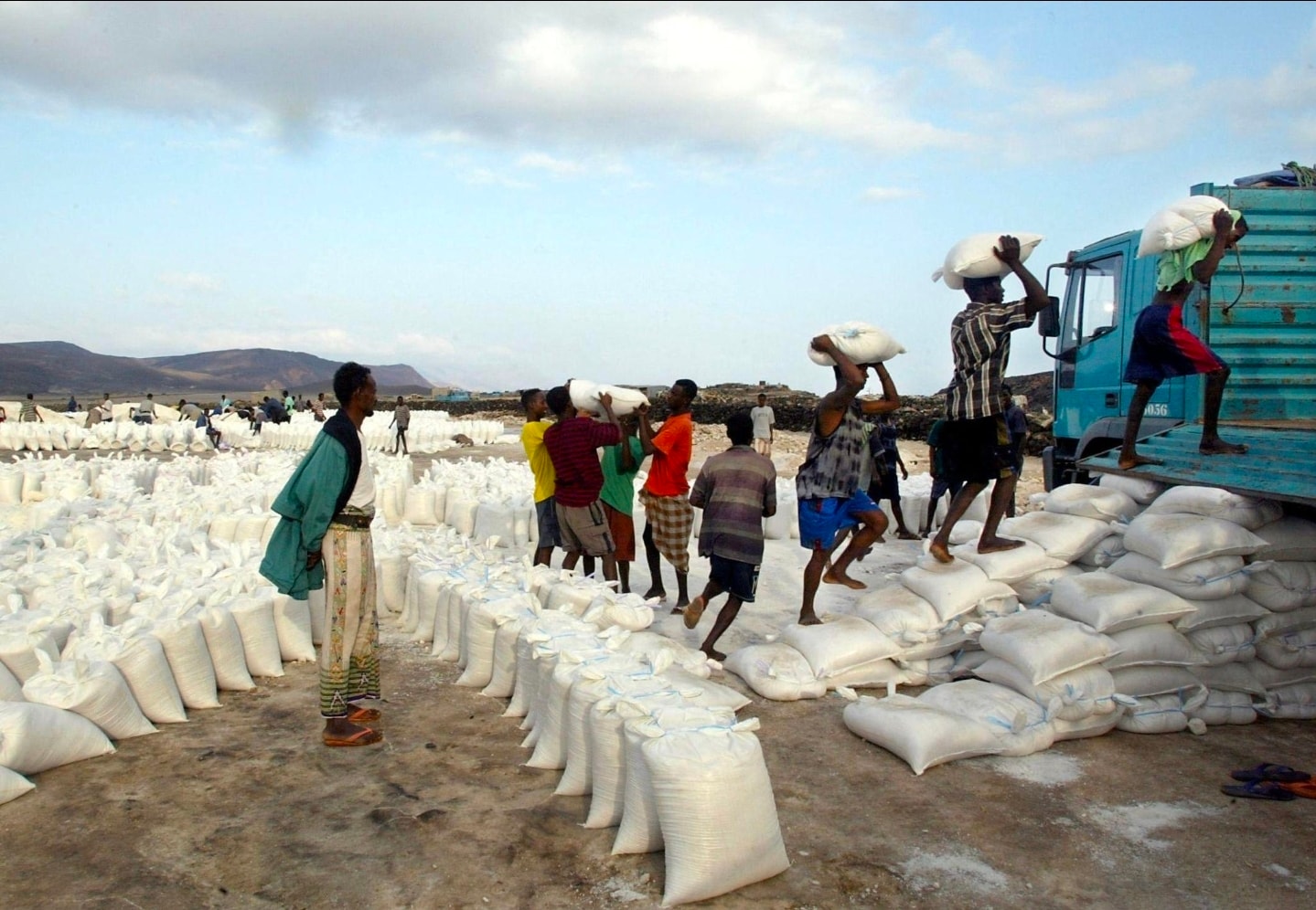 Workers loading sacks of Lac Assal salt onto a truck in the Djibouti landscape